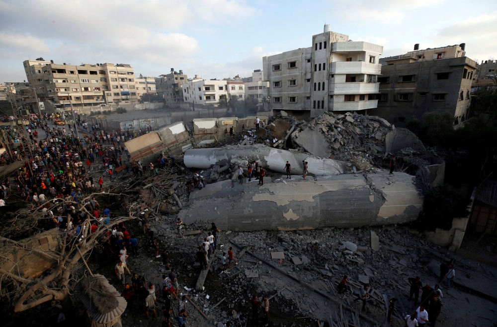 Palestinians gather around a building after it was bombed by an Israeli aircraft in Gaza City on Thursday. — Reuters