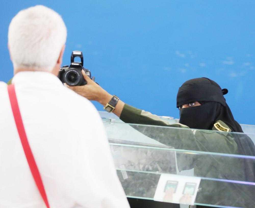 A female employee photographs an incoming pilgrim at Jeddah airport.