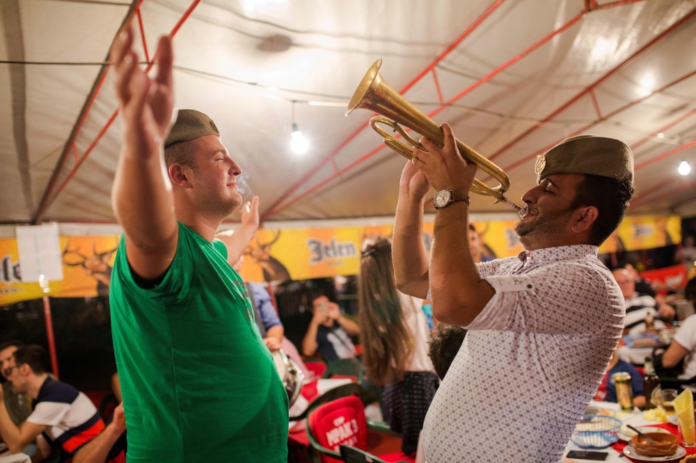 People dance as a musician plays the trumpet during the Guča Trumpet Festival in the Serbian village of Guca, about 160 km south of Belgrade on Sunday. - AFP