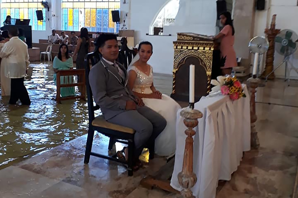 This handout photo taken from the facebook of Bautista Banares Tere, shows the bride Jobel Delos Angeles, 24, and her groom during their wedding amid a flooded church in Hagonoy town, Bulacan town, north of Manila on Saturday. - AFP