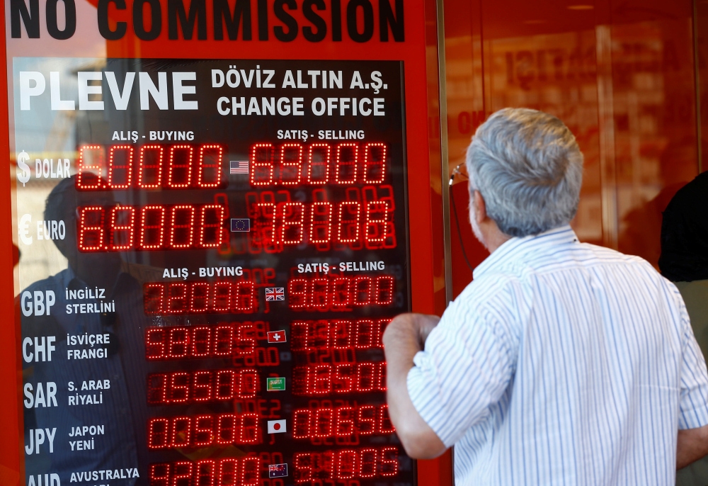 A man looks at the display board of a currency exchange office in Istanbul, Turkey on Monday. — Reuters