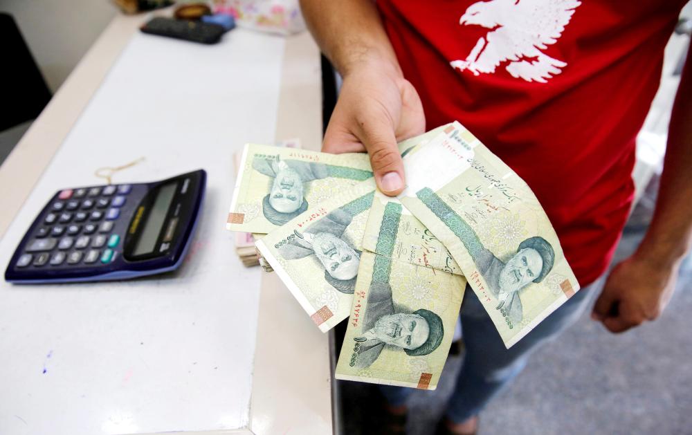 A vendor inspects Iranian rials at a currency exchange shop in Baghdad, Iraq. The rial has lost about half of its value since April in anticipation of the renewed US sanctions, driven mainly by heavy demand for dollars among ordinary Iranians trying to protect their savings. — File photo