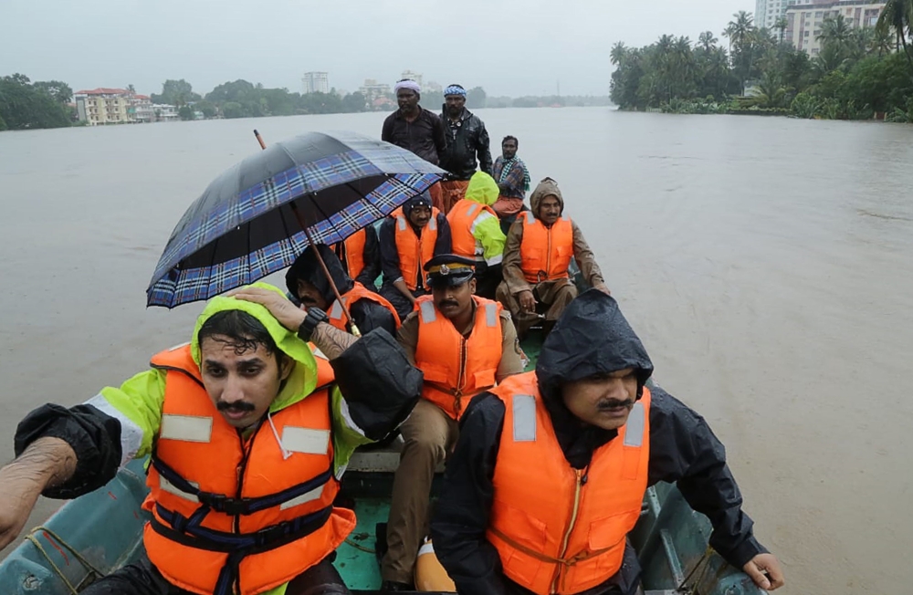 Indian fire and rescue personnel evacuate local residents in an boat flooded following monsoon rains at Aluva, in the Indian state of Kerala, on Thursday. — AFP