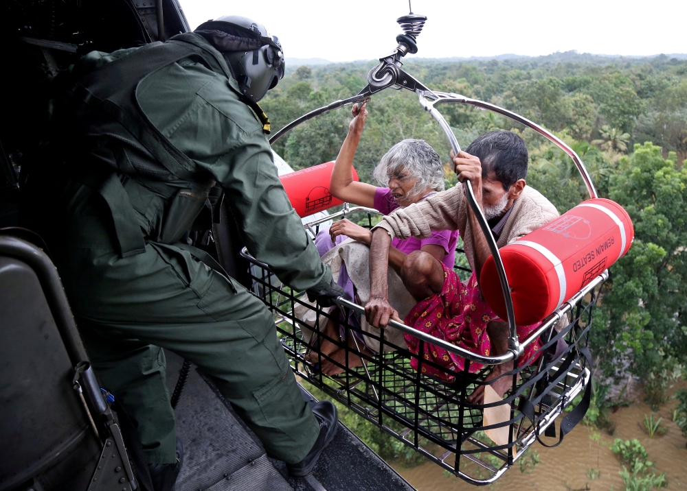 People wait for aid on the roof of their house at a flooded area in the southern state of Kerala, India, on Friday. — Reuters