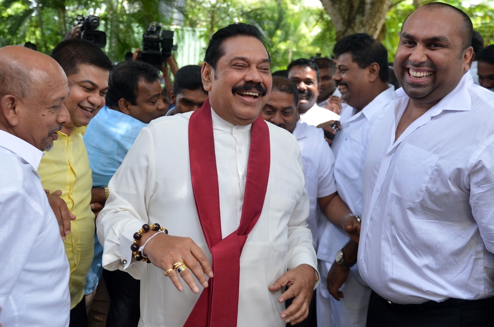 Former Sri Lankan President Mahinda Rajapaksa, center, jokes around with his supporters after police investigators visited him in Colombo on Friday to record a statement on the abduction and assault of a journalist. — AFP