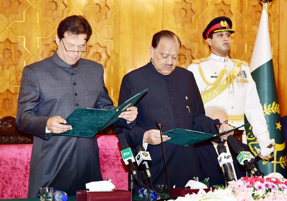 President of Pakistan Mamnoon Hussain, center, takes an oath from newly-appointed Prime Minister Imran Khan, left, during a ceremony in Islamabad. — AFP