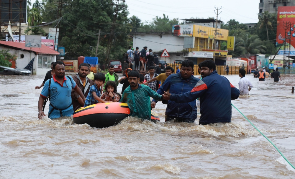 Indian volunteers and rescue personal evacuate local residents in a boat in a residential area at Aluva in Ernakulam district, Kerala, on Friday. — AFP