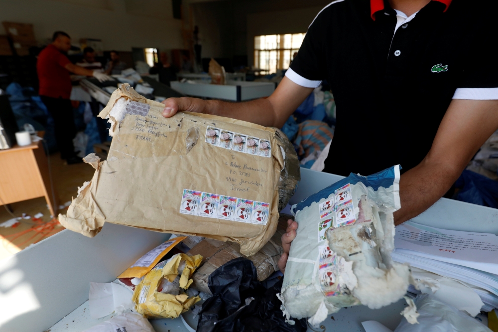 A Palestinian man inspects items sent by mail eight years ago after Israel allowed the letters and goods into the West Bank from Jordan, where they were being held, Jericho, in the occupied West Bank, on Sunday. — Reuters