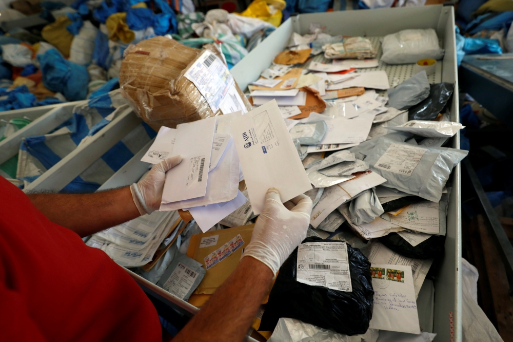 A Palestinian man inspects items sent by mail eight years ago after Israel allowed the letters and goods into the West Bank from Jordan, where they were being held, Jericho, in the occupied West Bank, on Sunday. — Reuters