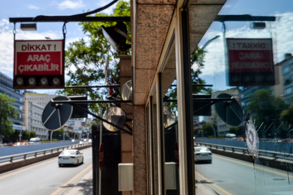 A car passes by a security booth with a bullet hole in a window at the entrance of the US Embassy in Ankara on Monday. — AFP