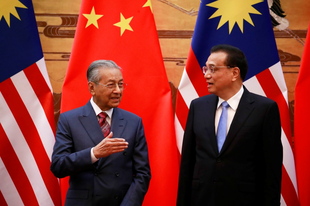 Malaysia's Prime Minister Mahathir Mohamad and China's Premier Li Keqiang chat during a signing ceremony at the Great Hall of the People in Beijing, China, on Monday. — AFP