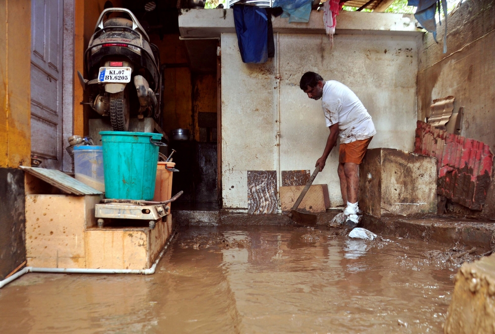 An Indian man cleans the muddy floor of a building in Kochi following widespread flooding in the south Indian state of Kerala on Monday. — AFP