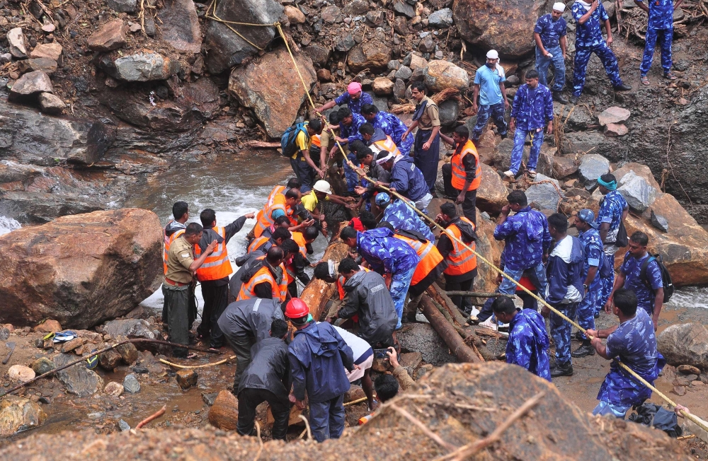 Indian Army personnel and Kerala state police work to build a temporary bridge over a rocky river following heavy flooding in Nelliyampathy in Palakkad district, in the Indian state of Kerala, on Monday. — AFP
