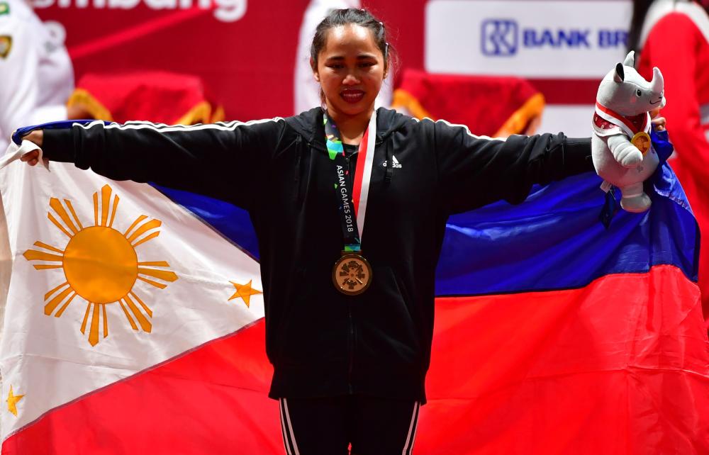 Hidilyn Diaz of Philippines celebrates at the podium during the victory ceremony for the women's 53kg weightlifting event during the 2018 Asian Games in Jakarta Tuesday. — AFP 