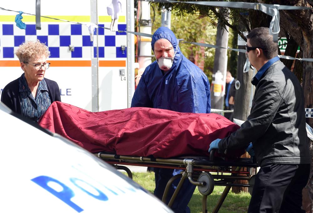 Forensic police and other officials remove a dead body from the crime site in the suburb of Australia’s western city of Perth on Monday. — AFP