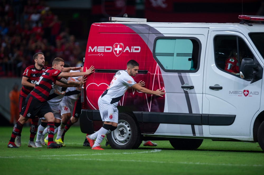 Brazilian football players are seen pushing the ambulance carrying Vasco da Gama's injured player Bruno Silva after it's engine failed to start on the field during the second half of their Brazilian national championship match at Mane Garrincha stadium in Brasilia on Sunday. - AFP