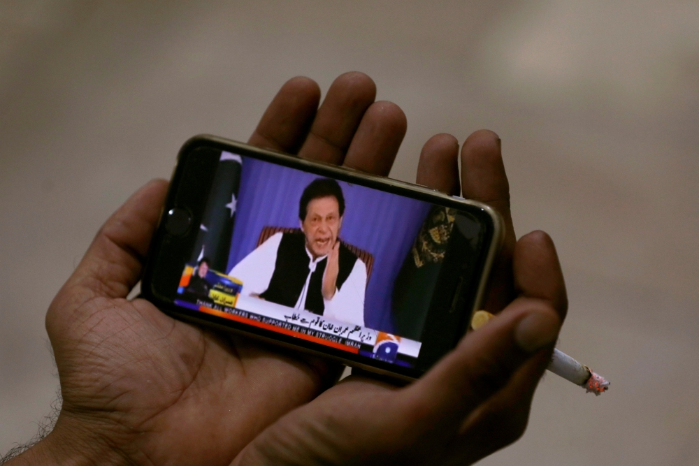 A journalist poses with a cell phone displaying Imran Khan, prime minister of Pakistan, speaking to the nation in his first televised address, in Karachi, Pakistan, in this Aug. 19, 2018 file photo. — Reuters