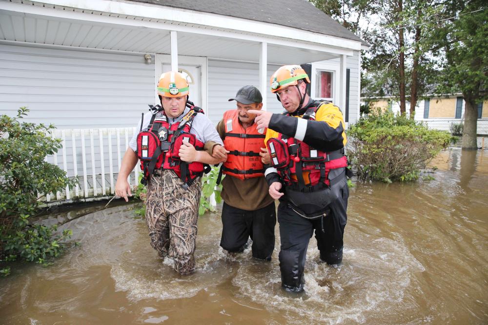 


Lumberton North Carolina Fire and Rescue members help a resident walk through flooded waters in Lumberton, North Carolina, on Monday. — AFP