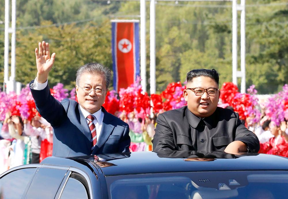 


North Korean leader Kim Jong Un, right, and South Korean President Moon Jae-in, left, wave to Pyongyang citizens from an open-topped vehicle as they drive through Pyongyang on Tuesday. — AFP