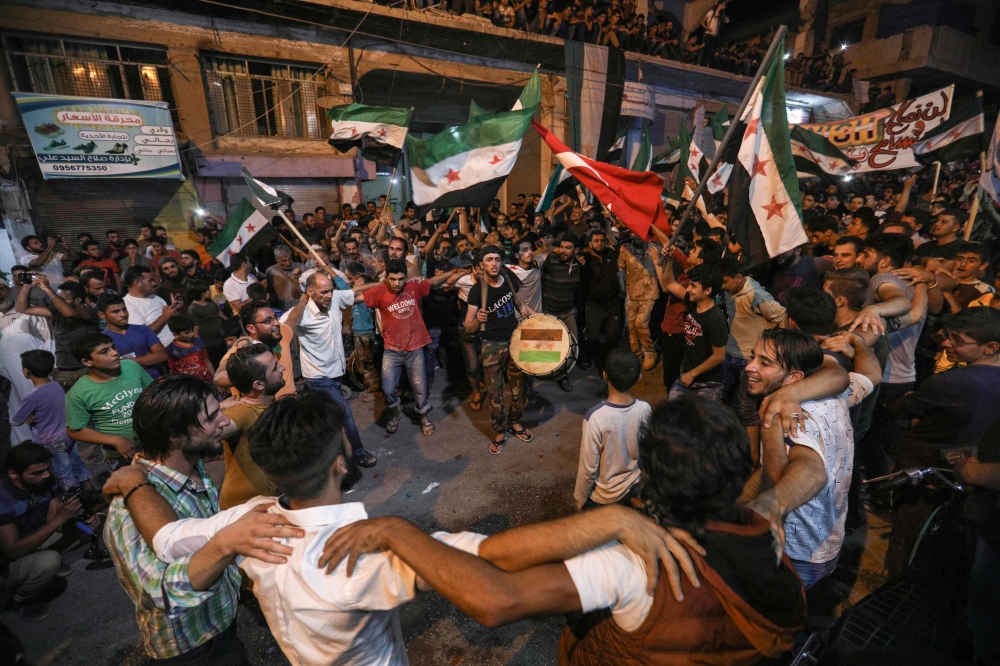 


Syrians dance, chant slogans and strike drums while others and wave flags of Turkey and the opposition, as they protest against the Syrian government during a demonstration in Binnish in the rebel-held northern Idlib province late Monday. — AFP