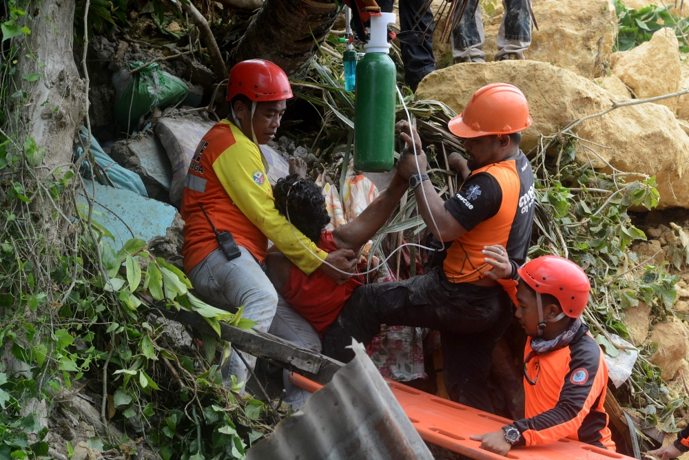 Rescue workers provide first aid to a rescued resident after a landslide triggered by monsoon rains hit a village in Naga City, Cebu province, in central Philippines, on Thursday. — AFP
