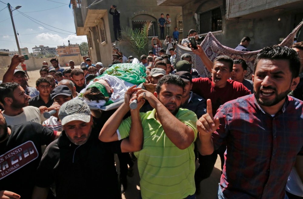Palestinian mourners carry the body of Mumin Abu Ayeda, 15, who was killed during a protest at the Israel-Gaza border fence, during his funeral in Rafah in the southern Gaza Strip on Thursday. — AFP