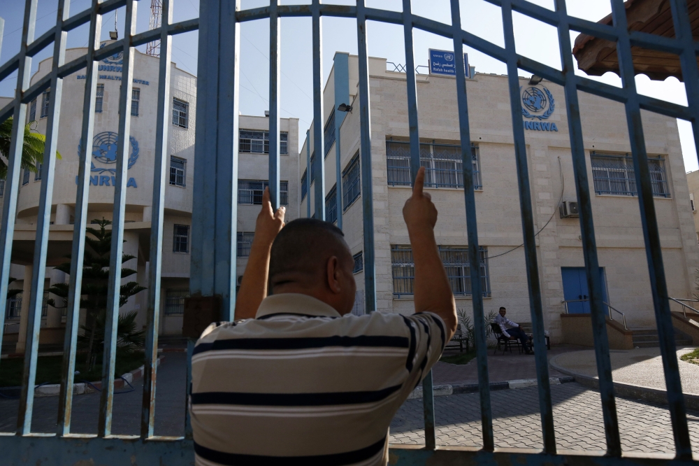 A Palestinian man stands outside the closed gate of United Nations Relief and Works Agency (UNRWA) during a strike of all UNRWA institutions in Rafah in the southern Gaza Strip, Monday. — AFP