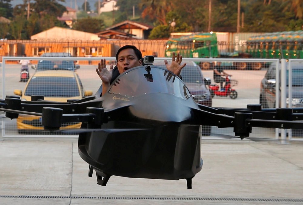 A journalist rides a drone flying car controlled by its inventor Kyxz Mendiola during its launch in the province of Batangas, Philippines, in this Sept. 23, 2018 file photo. — Reuters