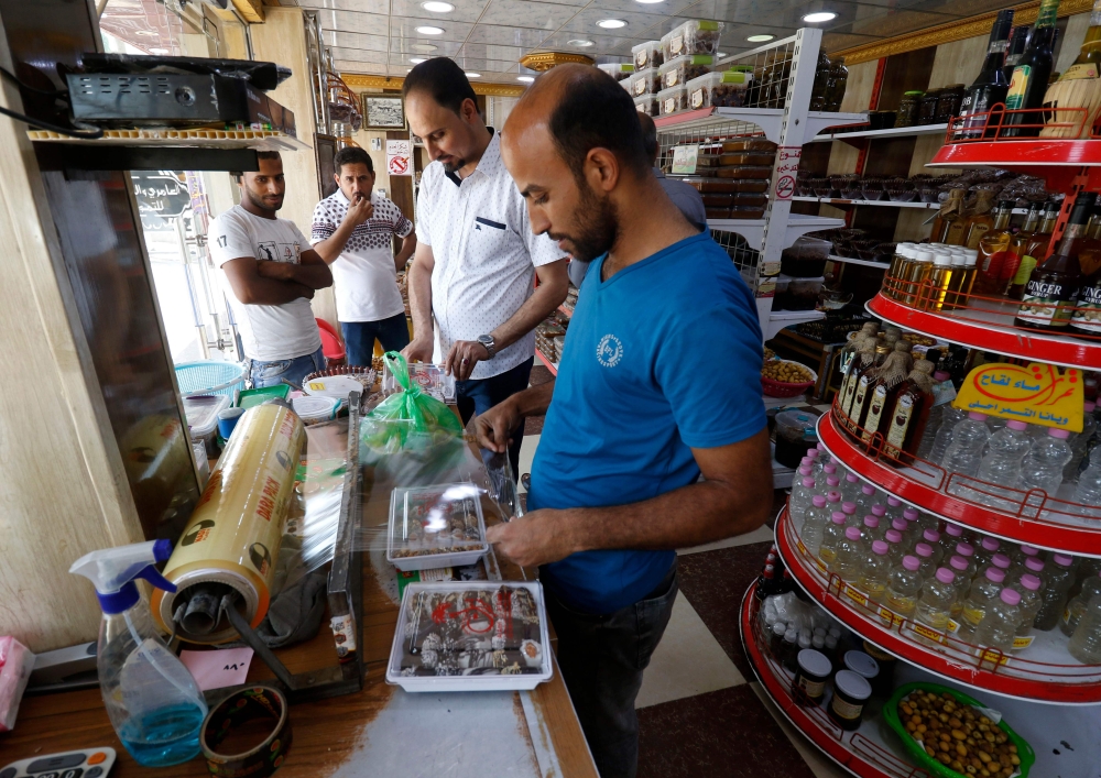 An Iraqi merchant wraps up a package of sweets at a shop selling dates and other date-related products in the region of Abu Al-Khasib, 25 km southeast of the southern city of Basra in this Aug. 31, 2018 file photo. — AFP