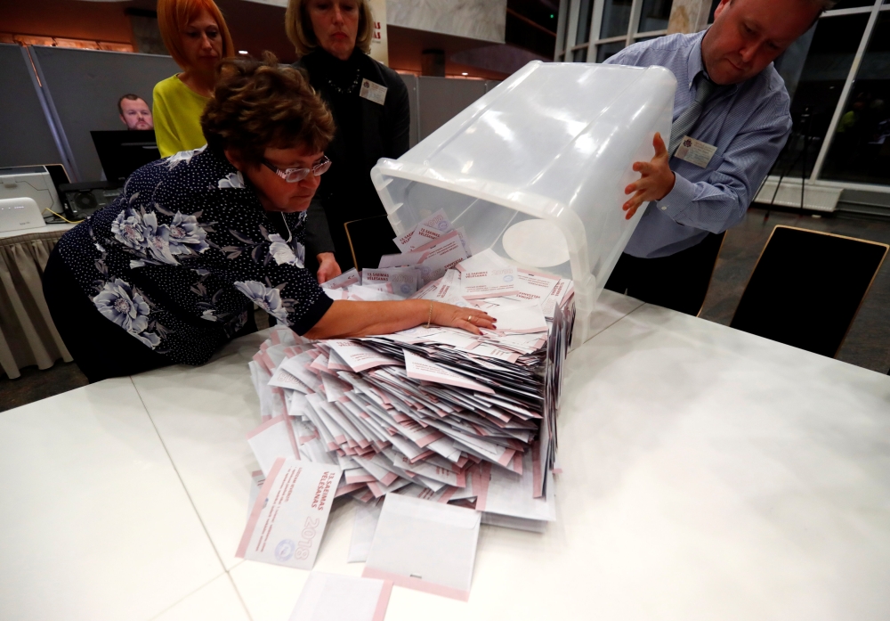 Election officials open ballot box for counting in Riga, Latvia on Saturday. — Reuters