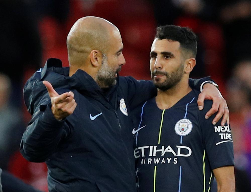 Manchester City manager Pep Guardiola speaks with Riyad Mahrez after the match against Liverpool in Anfield Sunday. — Reuters