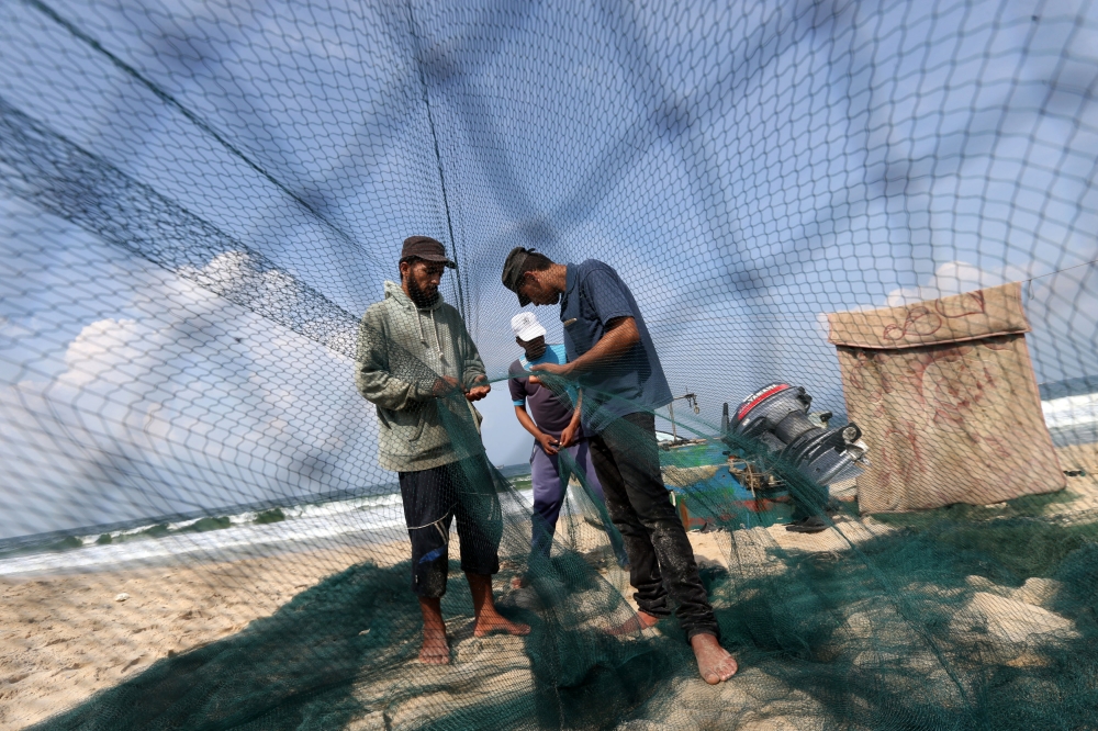Palestinian fishermen repair their net on a beach in the southern Gaza Strip in this Oct. 7, 2018 file photo. — Reuters