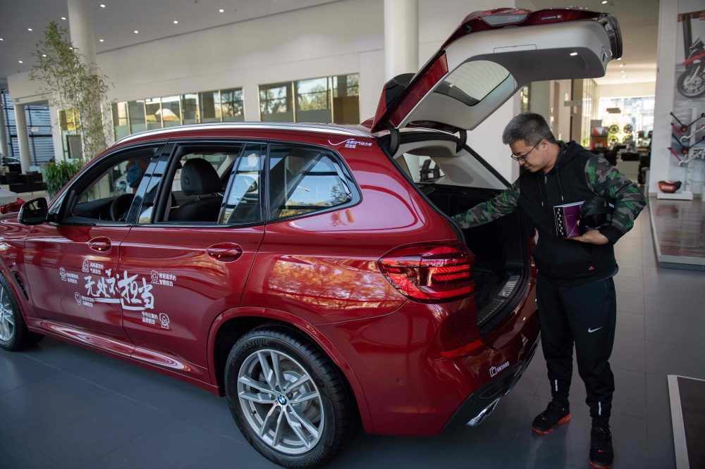 A customer inspects a BMW car on display at the German automaker's dealership in Beijing on Thursday. German luxury carmaker BMW announced  a plan to take control of its China joint-venture, the first foreign automaker to take advantage of Beijing's new ownership rules for the sector. — AFP