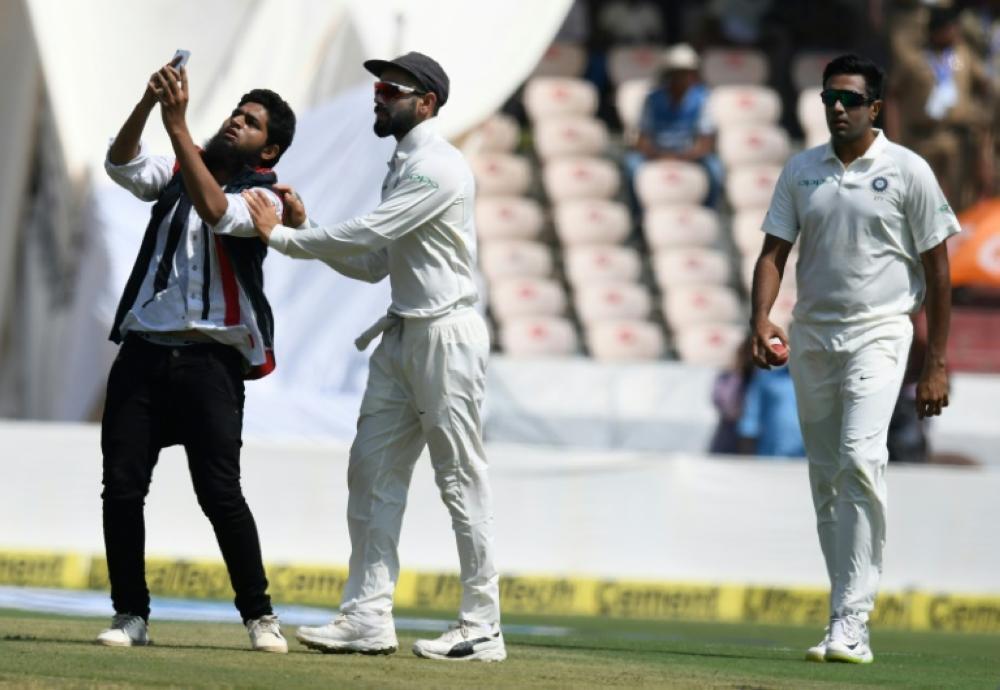 A fan takes a selfie with Indian captain Virat Kohli after invading the pitch on the first day of the second Test between India and the West Indies in Hyderabad. Also seen is Ravichandran Ashwin. — AFP