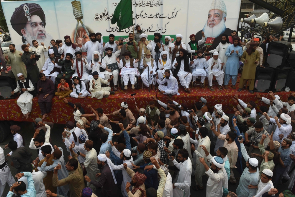 Supporters of Tehreek-e-Labaik Pakistan (TLP), a hardline religious political party, surround their party leader Khadim Hussain Rizvi, center top, during a protest rally in Lahore, Pakistan, on Friday. — AFP
