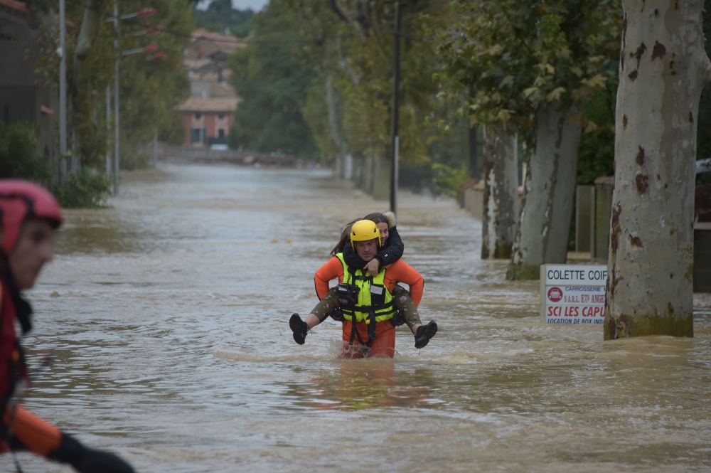 A firefighter helps a youngster in a flooded street during rescue operation following heavy rains that saw rivers bursting banks in Trebes, near Carcassone, southern France, on Monday. — AFP