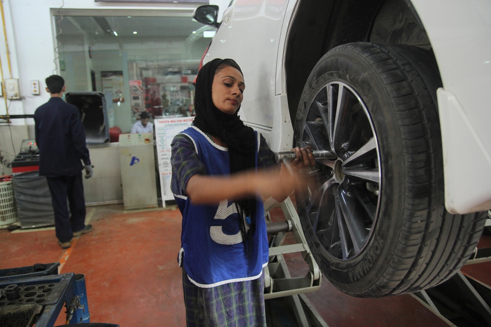 Pakistani motor mechanic Uzma Nawaz, 24, fixes a car at an auto workshop in Multan.  Since picking up a wrench as one of the first female car mechanics in conservative Pakistan, Uzma Nawaz has faced two common reactions: shock and surprise. And then a bit of respect. —AFP