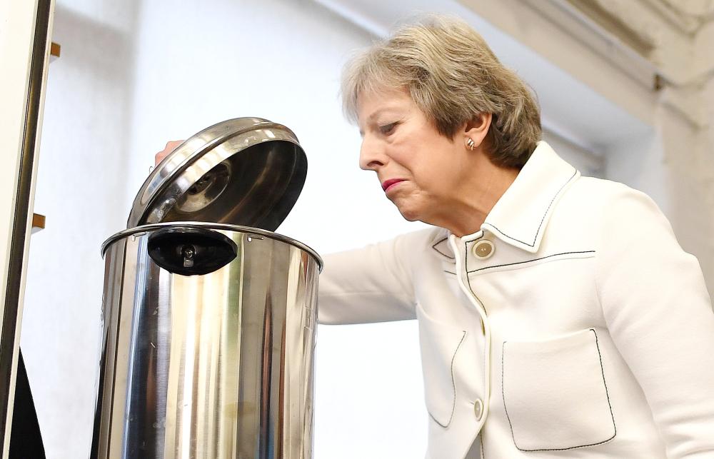


Britain’s Prime Minister Theresa May peers into a hot water urn as she helps make drinks during a visit to social group in Vauxhall, south London, on Monday. — AFP
