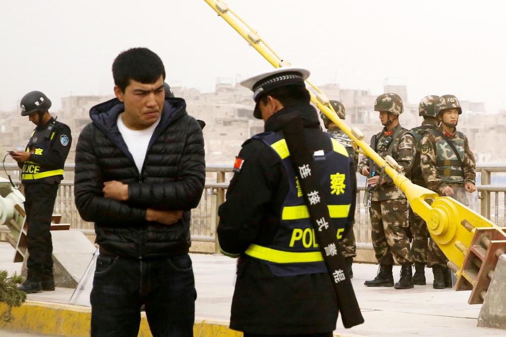 


A police officer checks the identity card of a man as security forces keep watch in a street in Kashgar, Xinjiang Uighur Autonomous Region, China, in this March 24, 2017 file photo. — Reuters