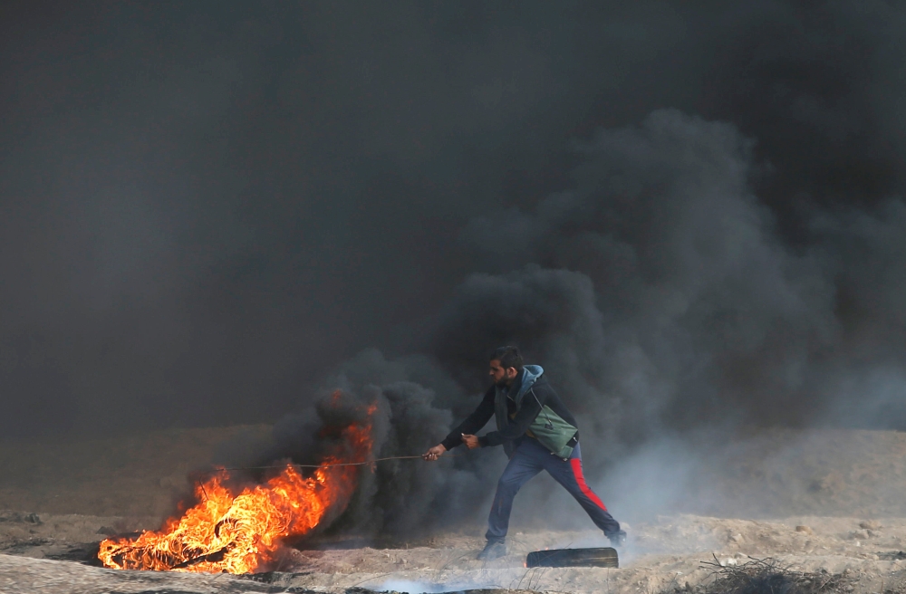Disabled Palestinian Saber Al Ashqar, aged 29, uses a slingshot to throw stones at Israeli forces during a demonstration near the border with Israel, east of Gaza City, on Friday. — AFP