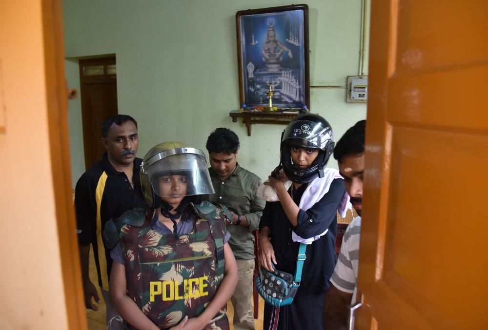 Indian journalist Kavitha Jakkal, left, and activist Rehana Fatima are pictured in protective gear in a building outside of the Lord Ayyappa temple complex at Sabarimala in India’s southern Kerala state in this Oct. 19, 2018 file photo after they were denied entry to the temple grounds by Hindu hardliners. — AFP