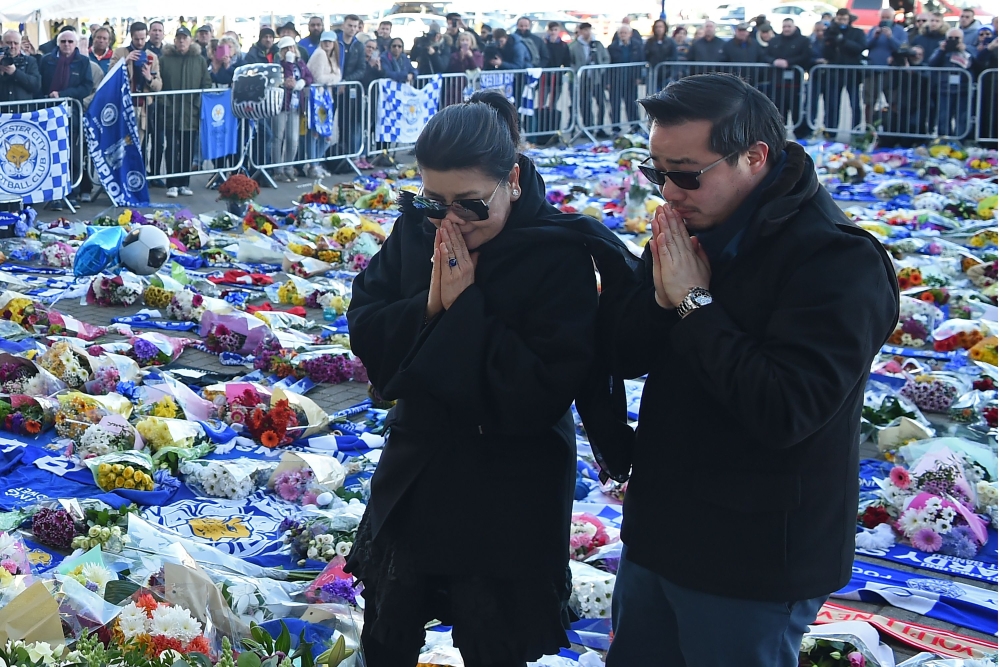 Aiyawatt Srivaddhanaprabha, right, and Aimon Srivaddhanaprabha, left, the son and wife of Leicester City’s Thai chairman Vichai Srivaddhanaprabha who died in a helicopter crash at the club's stadium, pray after laying wreathes among the tributes to the victims of the crash at Leicester City Football Club’s King Power Stadium in Leicester, eastern England, on Monday. — AFP