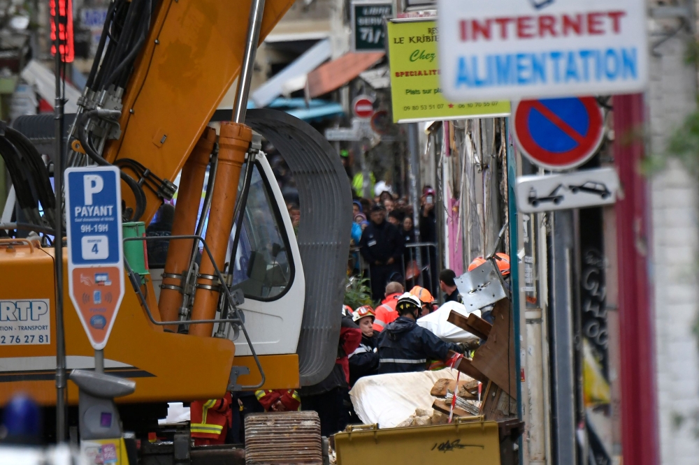 Firefighters evacuate a body from the site where two buildings collapsed in Marseille, France, on Tuesday. — AFP