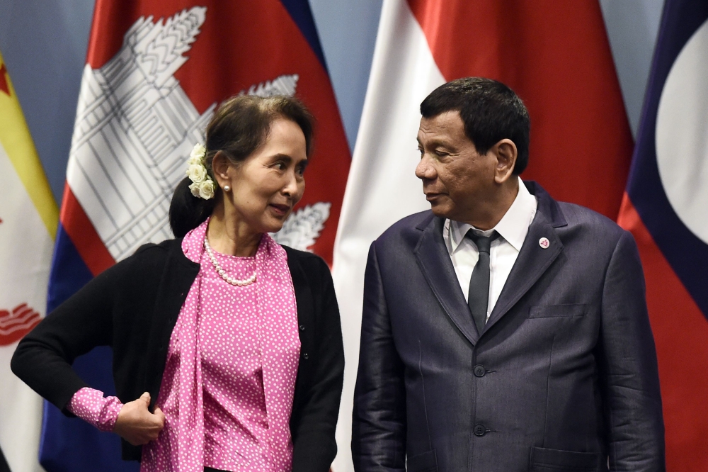 Philippine President Rodrigo Duterte, right, listens to Myanmar State Counselor Aung San Suu Kyi as they arrive on stage to pose for a group photo before the start of the ASEAN-Japan summit on the sidelines of the 33rd Association of Southeast Asian Nations (ASEAN) summit in Singapore on Wednesday. — AFP