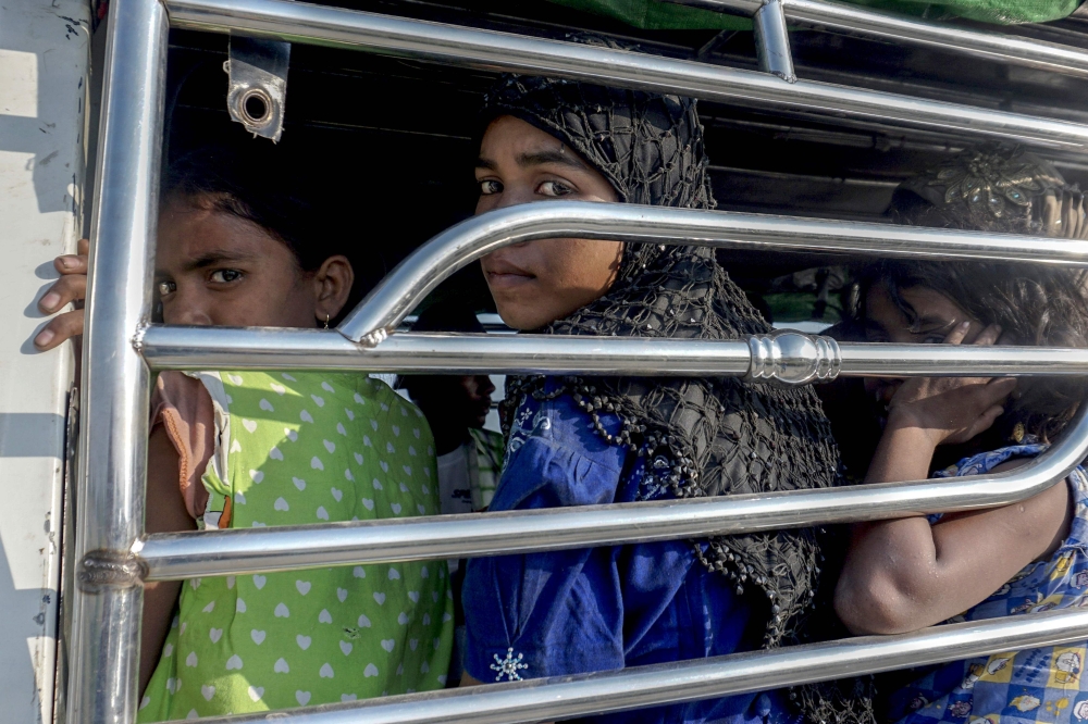 Rohingya Muslim women ride a police vehicle in Kyauktan township south of Yangon on Friday after their boat washed ashore. — AFP