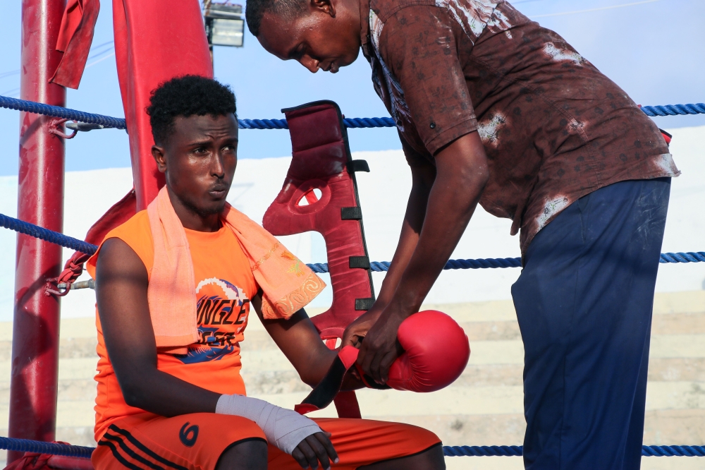 Somali boxer Abdiaziz Ali Shirar, 21-years-old, is helped with his glove by his coach during a boxing match in a ring installed at the Wish Stadium in Mogadishu.  Somalia has held its first boxing competition in over three decades, with young boxers in the conflict-torn nation dreaming of a career on the international stage. The three-day light-weight boxing competition, which wrapped up on Sunday. — AFP