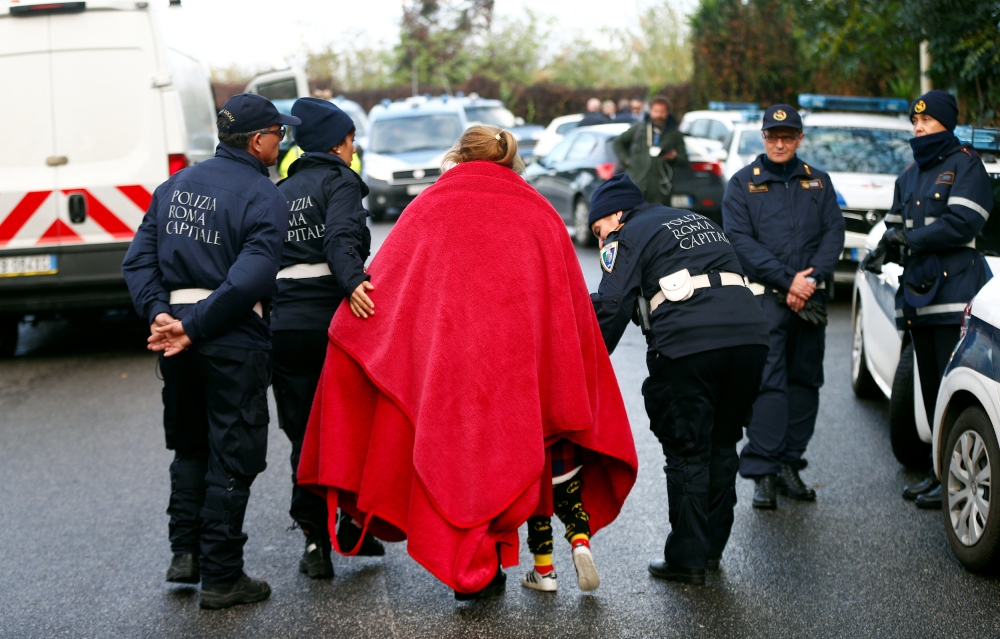 A person and a child are escorted by officers as local police confiscated a villa built illegally by an alleged Mafia family in Rome, Italy, on Tuesday. — Reuters