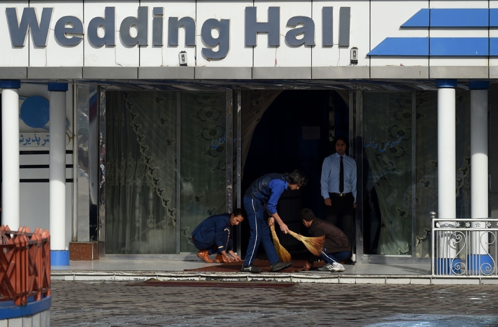 Afghan workers clean the area outside of a wedding hall a day after a deadly suicide attack in Kabul on Wednesday. — AFP