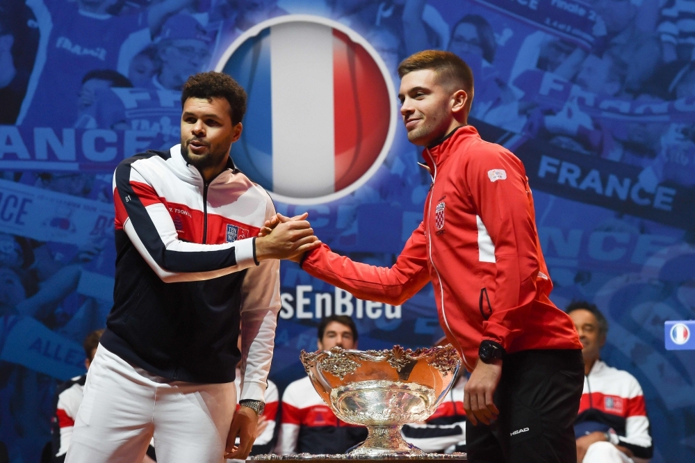 France's Jo-Wilfried Tsonga (L) and Croatia's Borna Coric shake hands next to the  Davis Cup trophy  on the eve of the Davis Cup tennis final between France and Croatia at the Pierre Mauroy Stadium in Villeneuve-d'Ascq, northern France, on Thursday. — AFP