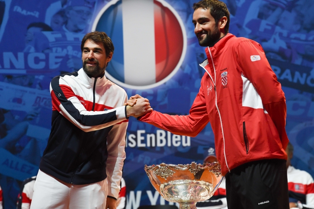 France's Jo-Wilfried Tsonga (L) and Croatia's Borna Coric shake hands next to the  Davis Cup trophy  on the eve of the Davis Cup tennis final between France and Croatia at the Pierre Mauroy Stadium in Villeneuve-d'Ascq, northern France, on Thursday. — AFP